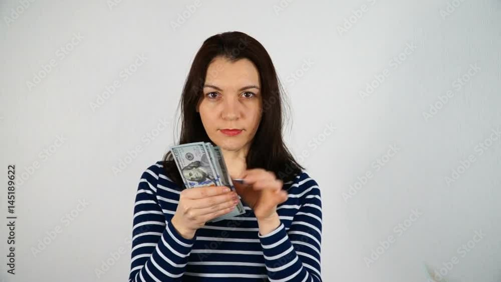 Woman on white background posing. The model holds a stack of hundred-dollar bills. Woman on white background posing. The model holds a stack of hundred-dollar bills.
