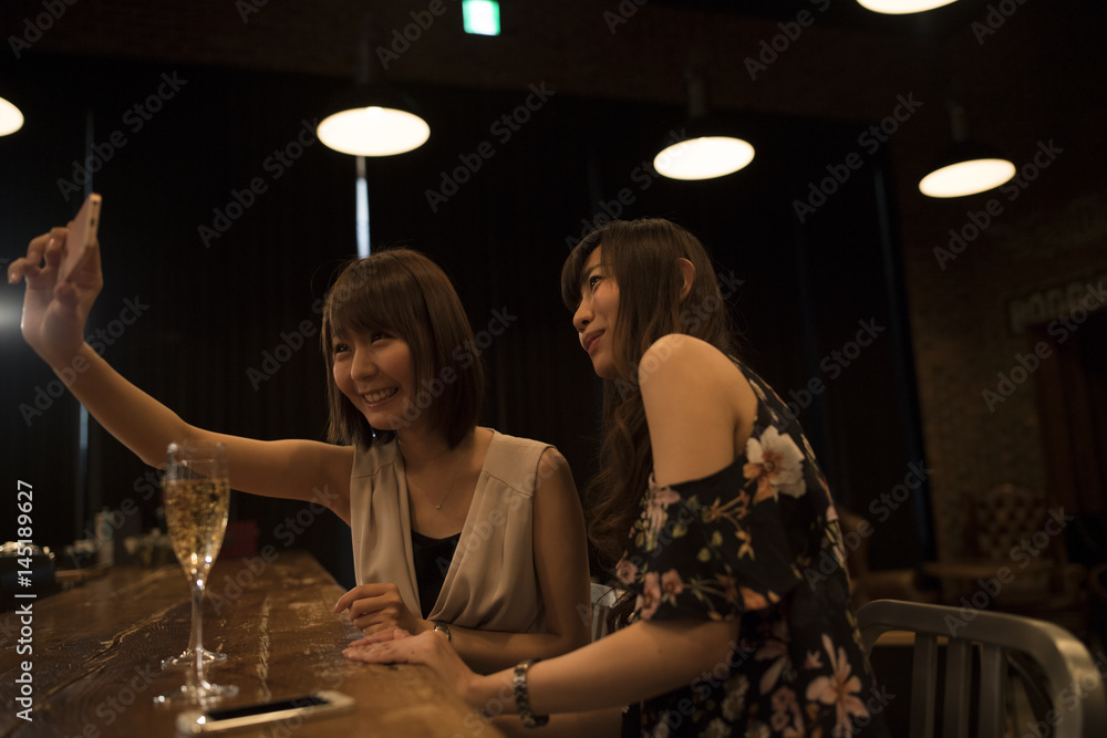 Two ladies are shooting on the smartphone at the bar