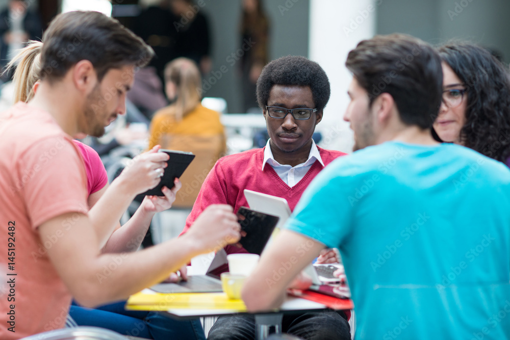 A group of teenagers sitting at the table in cafe, using laptop and drinking orange juice. A group of teenagers sitting at the table in cafe, using laptop and drinking orange juice.