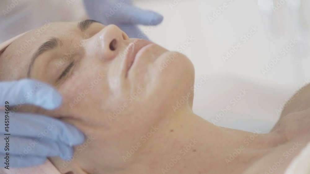 Woman getting massage of face after botox injections in the beauty salon Woman getting massage of face after botox injections in the beauty salon