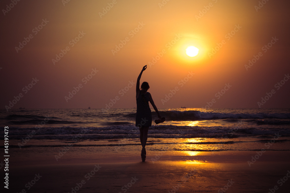 Young woman like a ballet dancer at sunset in Arambol beach, North Goa, India