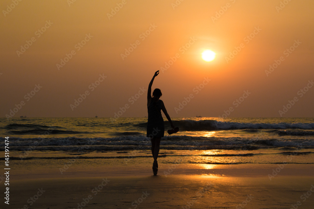 Ballet dancer's silhouette by the sea in sunset light in Arambol beach, North Goa, India