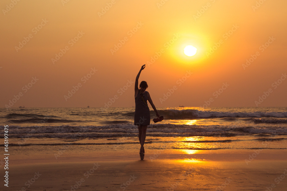 Amazing sunset portrait of the silhouette woman in Arambol beach, North Goa, India