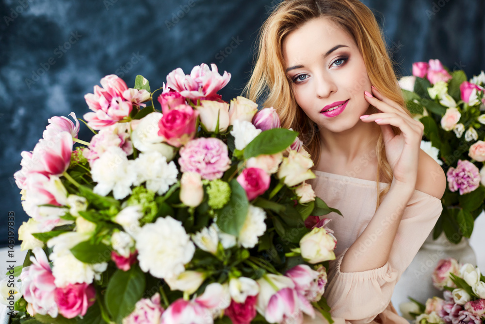 Portrait of a young blonde woman in flowers. Woman's face with make-up and hairstyle Portrait of a young blonde woman in flowers. Woman's face with make-up and hairstyle
