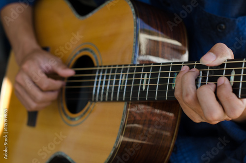 .A young boy sitting acoustic guitar happily.