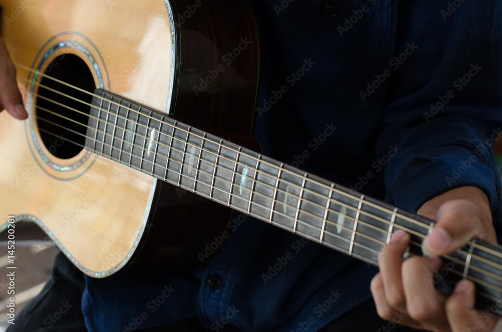 Fototapeta premium .A young boy sitting acoustic guitar happily.