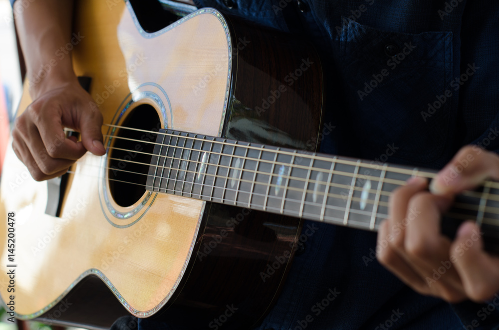 Fototapeta .A young boy sitting acoustic guitar happily.