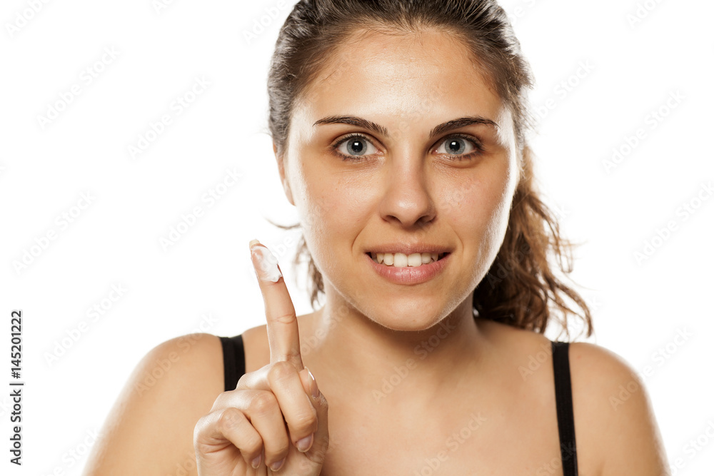 A young lady holding a face cream on her finger A young lady holding a face cream on her finger