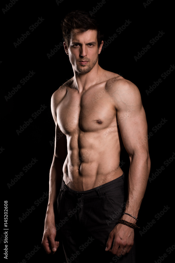 Fototapeta premium Strong muscular athlete posing on black