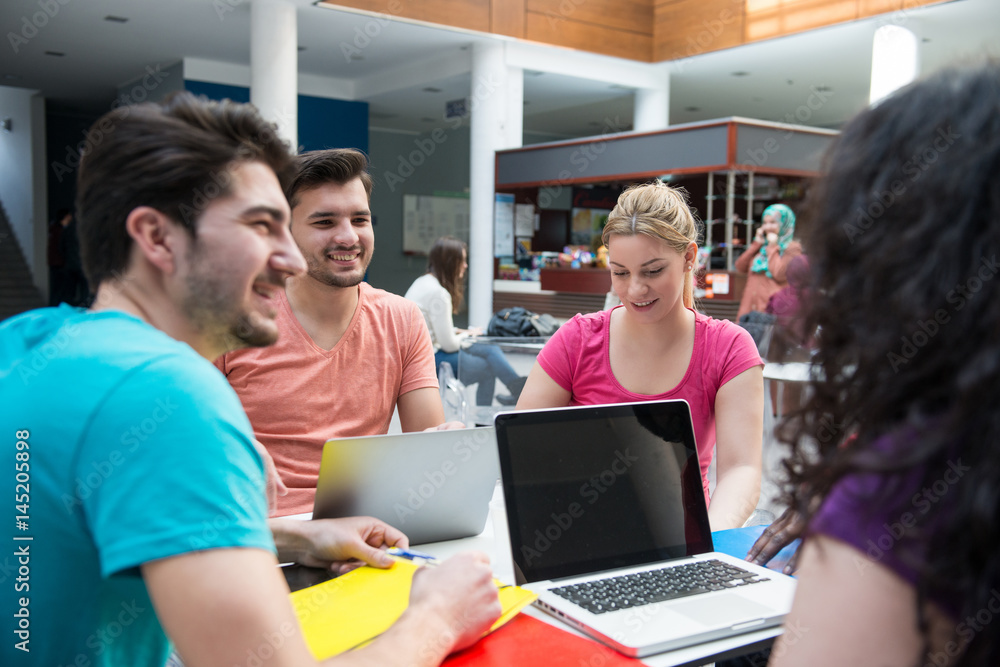 A group of teenagers sitting at the table in cafe, using laptop and drinking orange juice. A group of teenagers sitting at the table in cafe, using laptop and drinking orange juice.