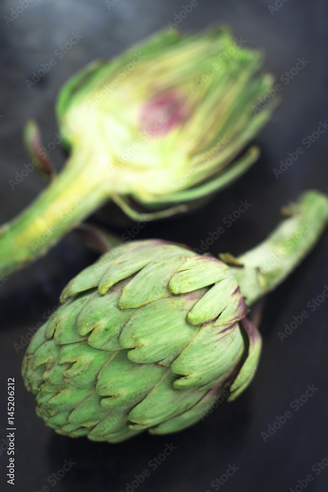 Fototapeta premium Fresh organic opened artichokes over a dark background
