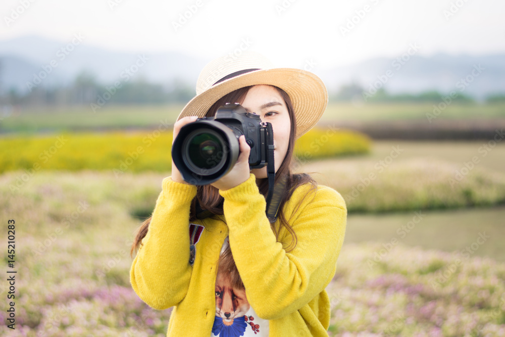 Naklejka premium Asian woman photographer is enjoy travel at flower field.