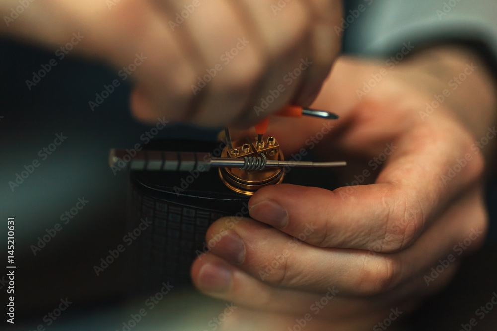 Vape after-sales service of the electronic cigarette. Male hands regulate e-cig coils. Personal vaporizer. Vape after-sales service of the electronic cigarette. Male hands regulate e-cig coils. Personal vaporizer.