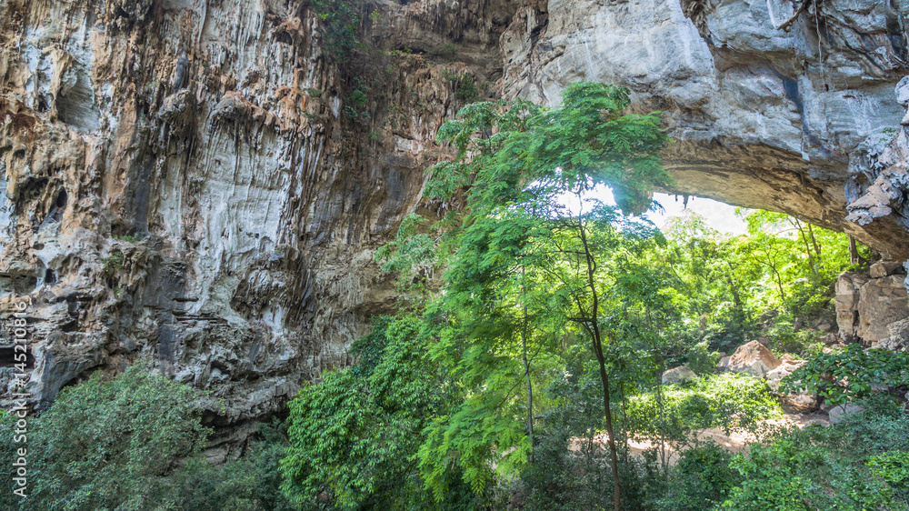 aerial photography above amazing cave. Tham Than Lod Yai is the big cave and have one hole on the top of the cave. it is a short cave there have waterfall pass inside through to another cave
