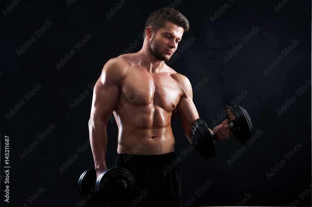 Horizontal studio shot of a young sexy male athlete exercising with heavy weights on black background posing shirtless showing off his hot toned ripped body confidence masculinity ambition motivation.