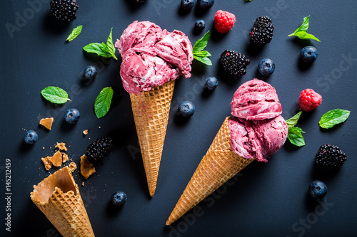 Homemade ice cream with berry fruits in waffels on blackboard