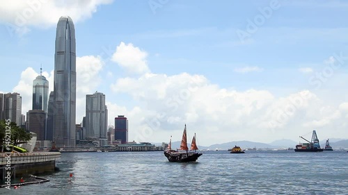 Chinese Junkboat sailing across Victoria Harbour and city skyline, Hong Kong. photo