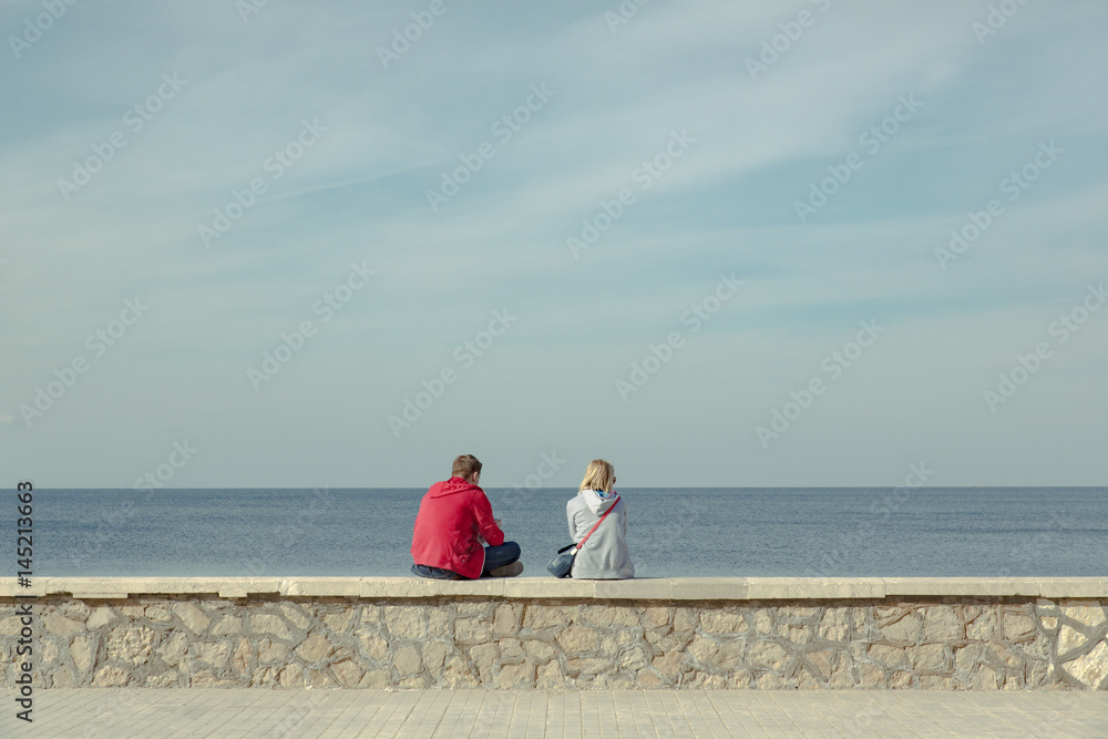 A young couple sitting in front of the sea