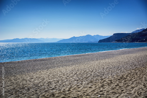 Empty sandy beach during the day under a clear blue sky