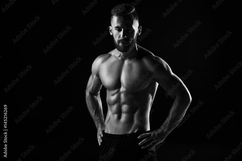 The torso of attractive male body builder on black background. The torso of attractive male body builder on black background.