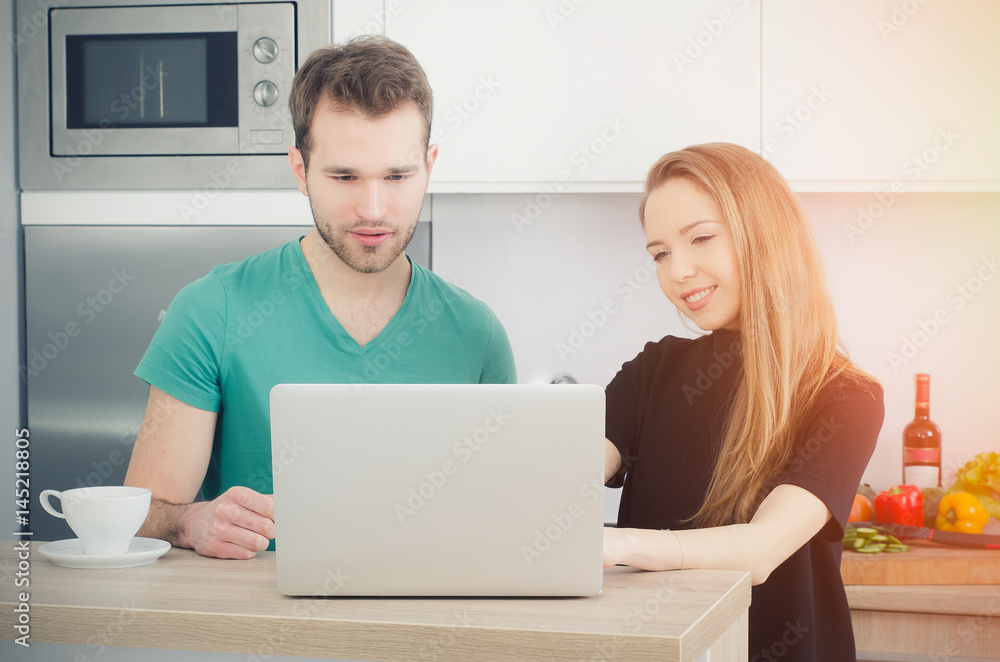 Couple uses the computer in the kitchen Couple uses the computer in the kitchen