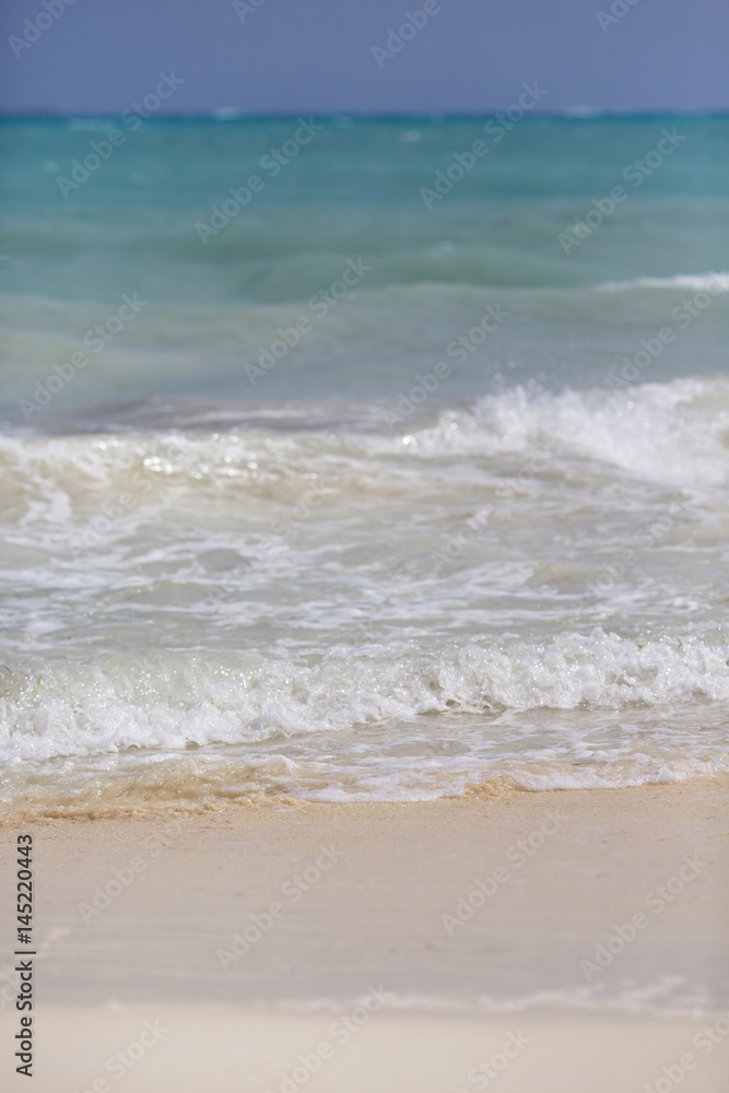Waves hitting the beach. White sand beach with turquoise sea water.