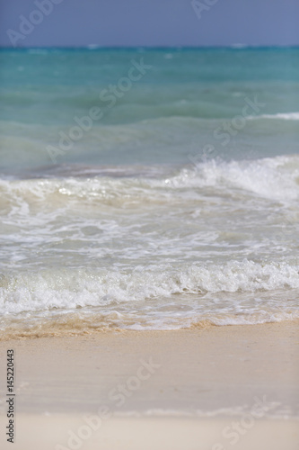 Waves hitting the beach. White sand beach with turquoise sea water.