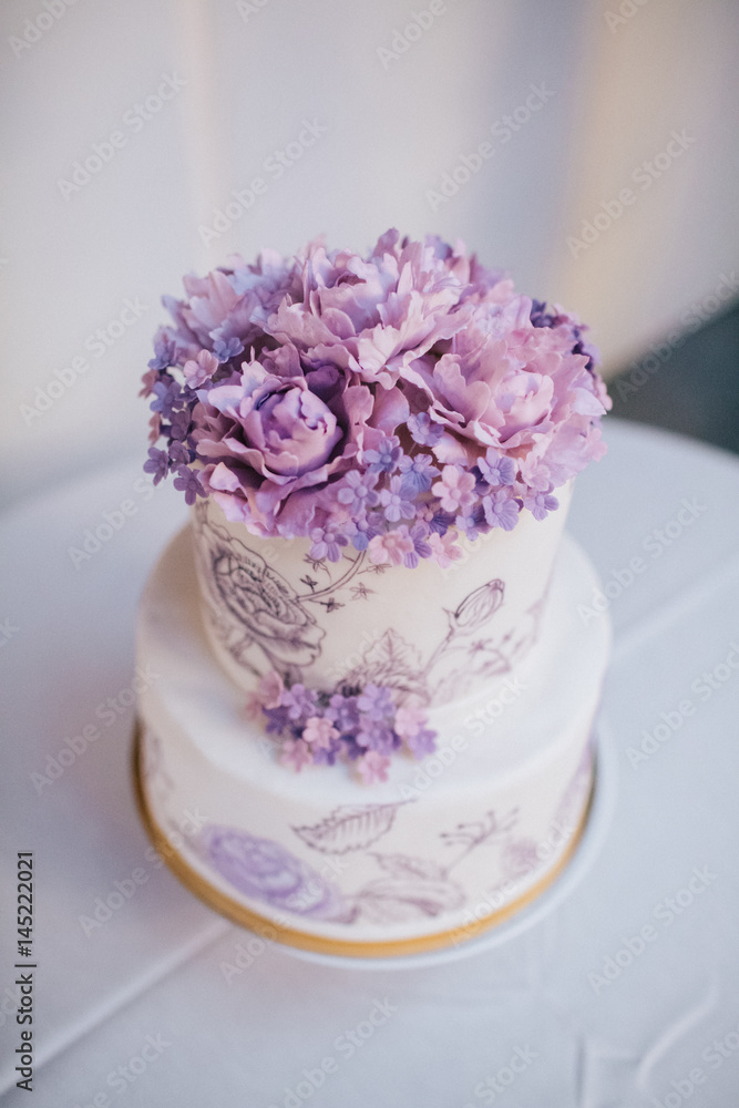 Violet flowers on the top of white tired cake Violet flowers on the top of white tired cake