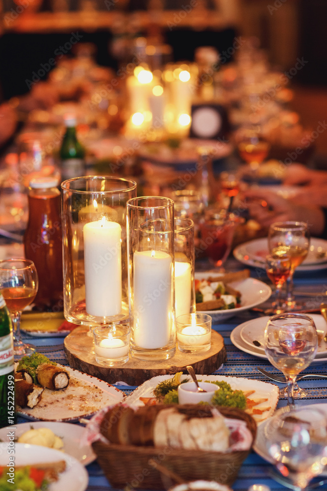 Wooden dishes with glass vases and candles stand on dinner table