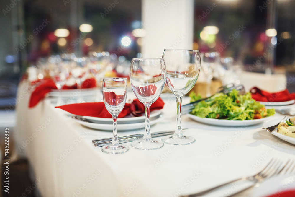 Three glasses stand by white plate with red napkins Three glasses stand by white plate with red napkins