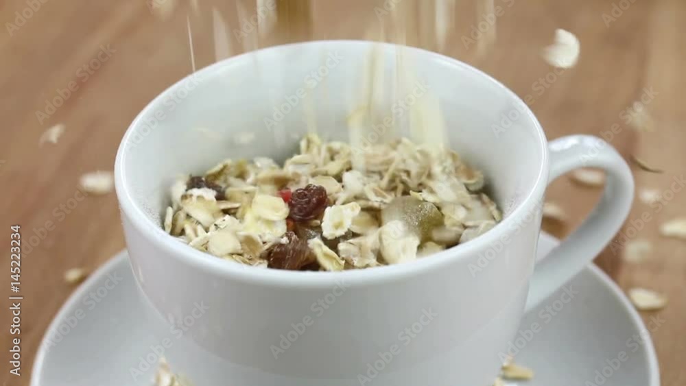 Falling muesli cereal into a white cup Falling muesli cereal into a white cup