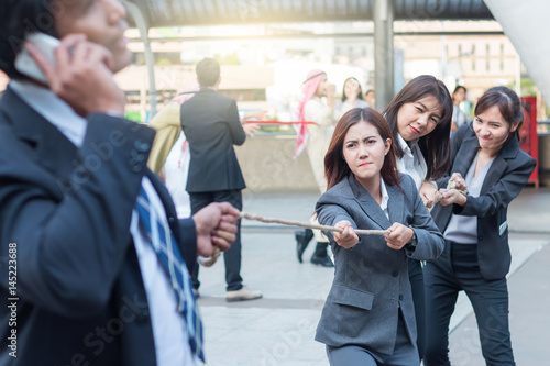 Group of woman pulling a rope competing with a businessman