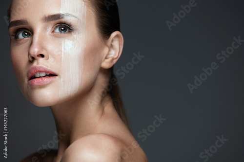 Facial Makeup. Sexy Woman With Cream Mask On Face Skin photo