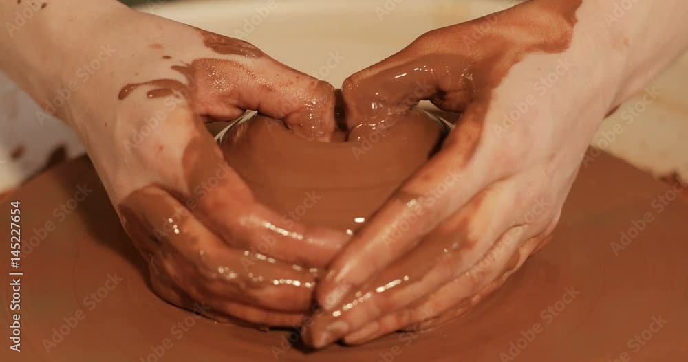 Close up of hands working clay on potter's wheel, Top view, close-up view Close up of hands working clay on potter's wheel, Top view, close-up view
