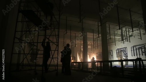 Silhouettes of workers lit by welding flashes photo