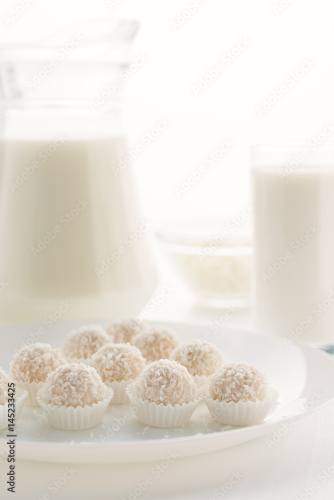 Raffaello candy in baskets on a plate, with milk in a glass and jug, cottage cheese in a bowl in the background, on a white table, in a high key, with space for text Raffaello candy in baskets on a plate, with milk in a glass and jug, cottage cheese in a bowl in the background, on a white table, in a high key, with space for text