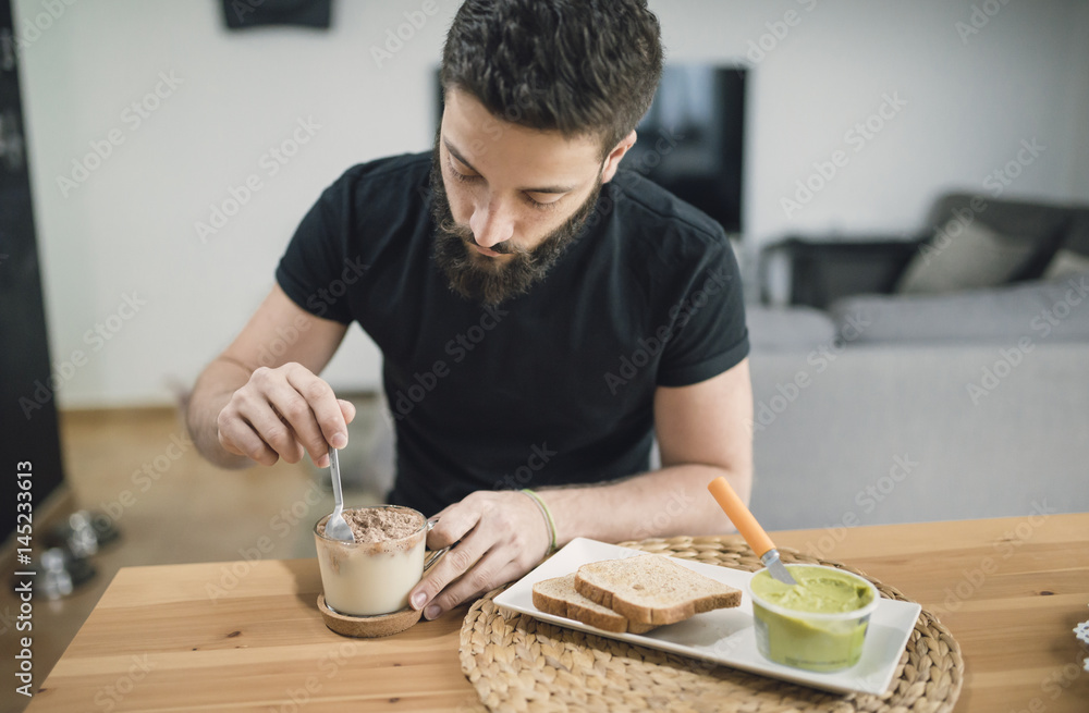 Young man preparing his breakfast at home, mixing cocoa and milk Young man preparing his breakfast at home, mixing cocoa and milk