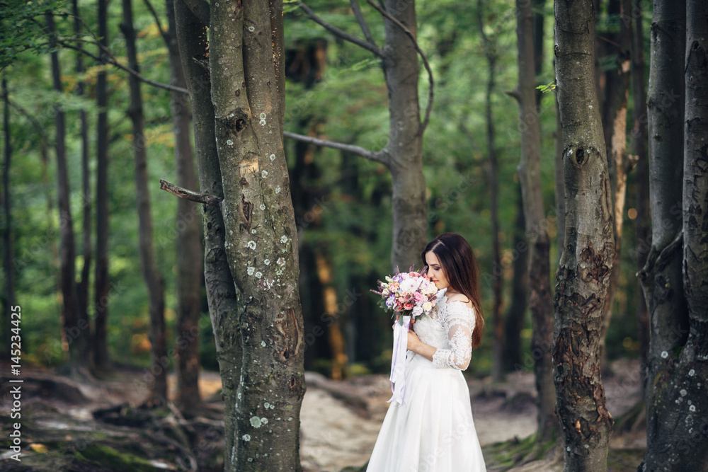 The charming bride stands near trees