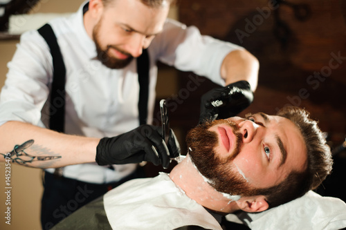 Master cuts hair and beard of men in the barbershop