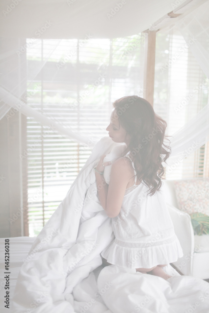 Beautiful brunette girl wakes up in the morning in her bed at home