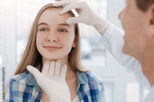 Careful dermatologist examining patient face at work photo