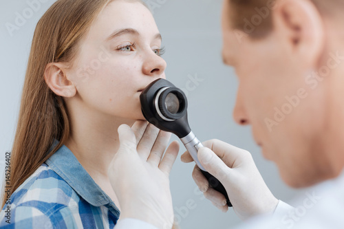 Serious young girl having appointment with dermatologist in the clinic