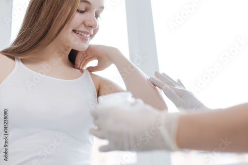 Caring medical specialist applying cream on patient arm in the clinic