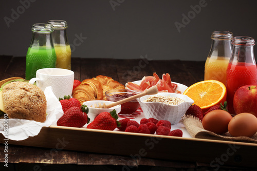 breakfast on table with bread rolls, croissants, coffe and juice