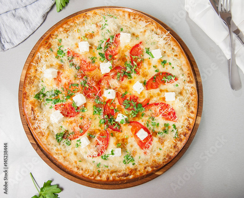 Top view Four cheese pizza quattro fromaggi on a rustic wooden board on the table with ingridients. Selective fovus photo