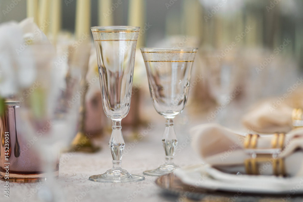 Crystal glasses with golden design stand on dinner table Crystal glasses with golden design stand on dinner table