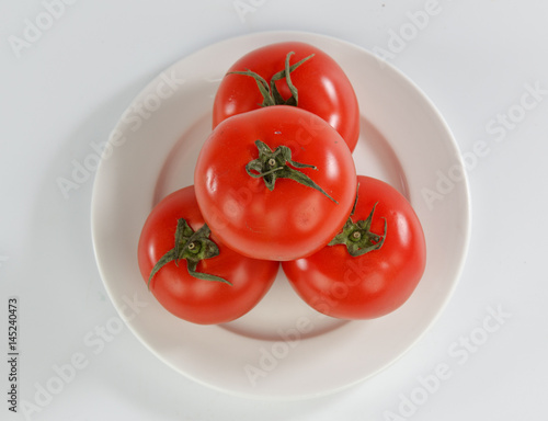 tomatoes on a plate isolated on white background © RomixImage