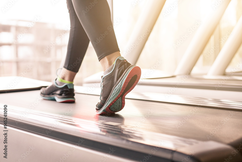 Woman running in a gym on a treadmill concept for exercising, fitness and healthy lifestyle Woman running in a gym on a treadmill concept for exercising, fitness and healthy lifestyle