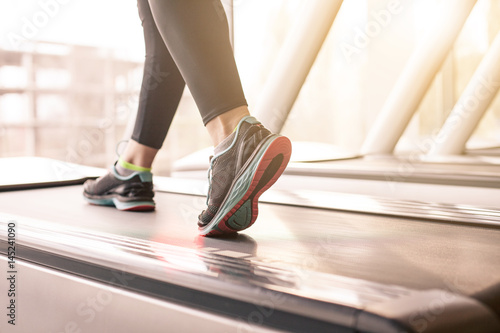 Woman running in a gym on a treadmill concept for exercising, fitness and healthy lifestyle