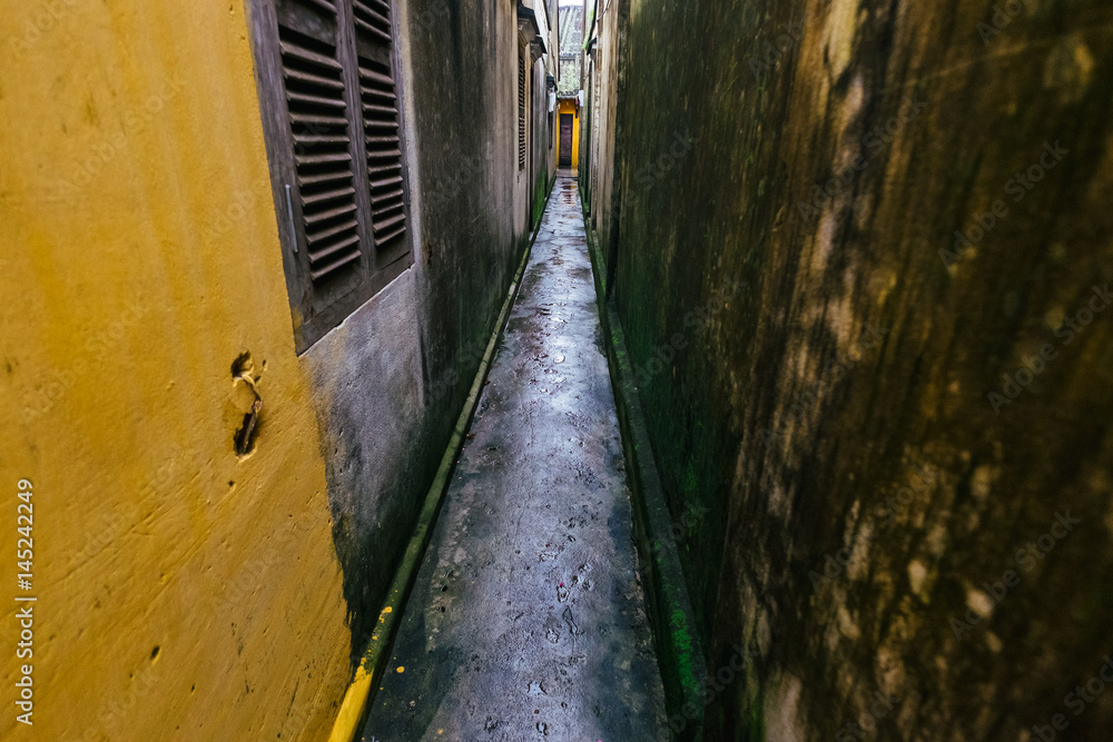 Narrow path between yellow and grey buildings